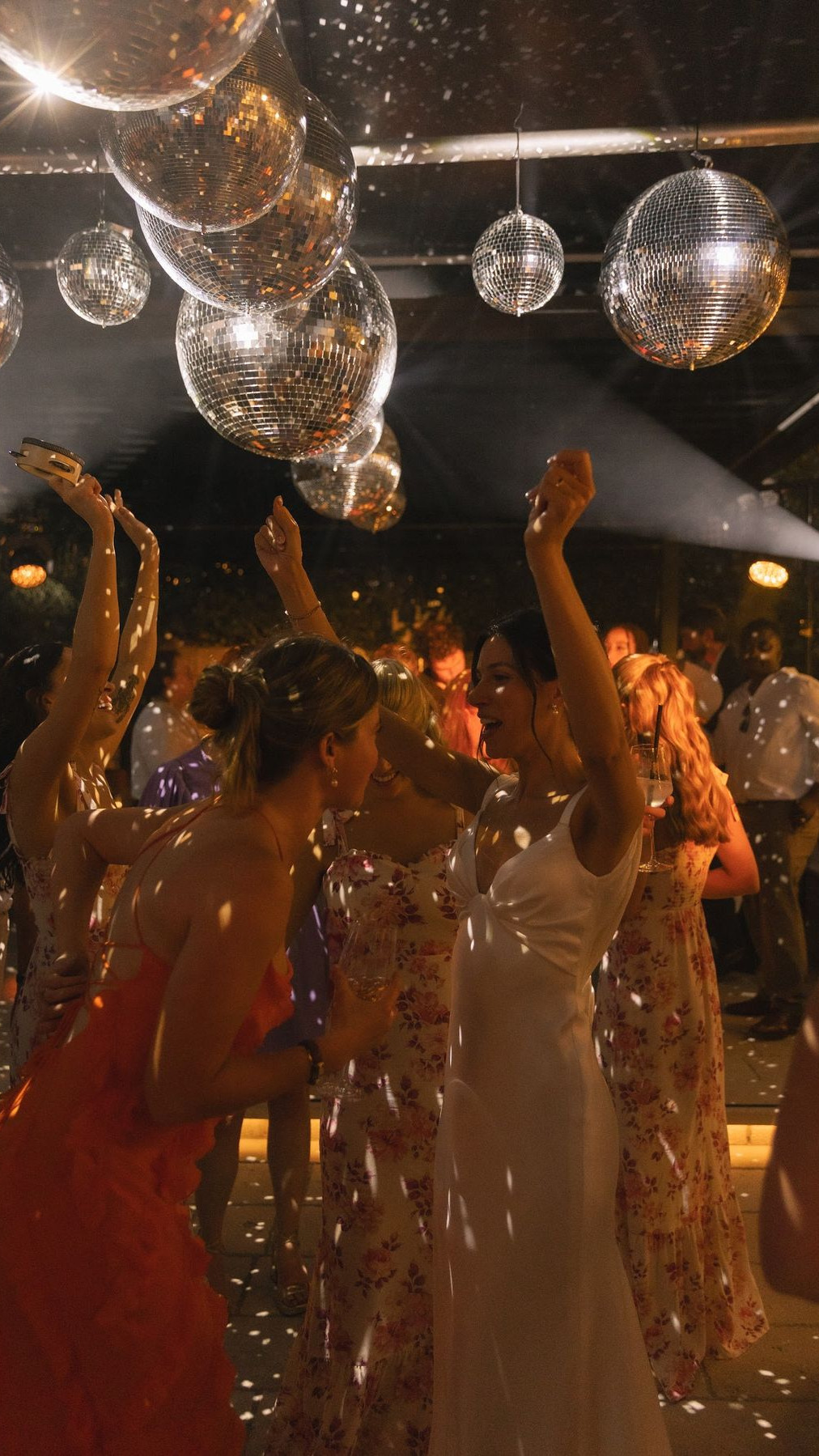 Elegantly dressed guests dancing under a glitterball on the dancefloor, illustrative of the evening entertainment and celebrations hosted at Weir Bank Estate, Bray-on-Thames, Berkshire.
